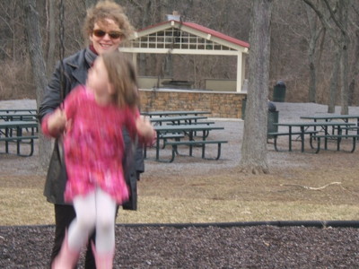 woman pushing girl on swing